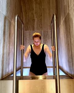 a woman in a black dress standing in front of two metal poles at Kusthotellet Styrsö in Styrsö