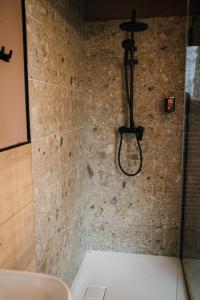 a shower in a bathroom with a stone wall at Pinja gozdne hiške in Črniče +33 photos