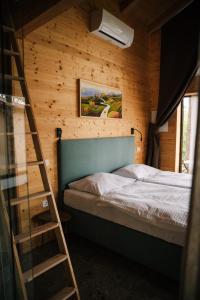 a bedroom with a ladder next to a bed at Pinja gozdne hiške in Črniče