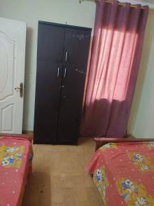 a room with two beds and a cabinet with red curtains at Soukaina home in Sintrīs