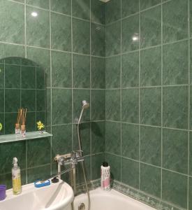 a green tiled bathroom with a tub and a sink at Central apartments in Sumy