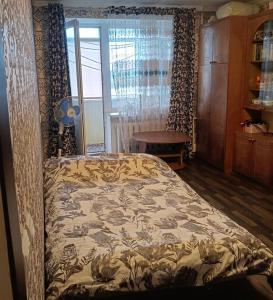 a bedroom with a bed and a table and a window at Central apartments in Sumy