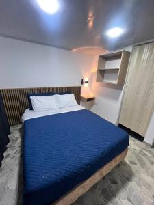 a bedroom with a bed with a blue blanket at Hospedaje ZIG ZAG 2 in Tocancipá