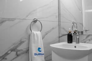 a bathroom with a sink and a white towel at BluWave Luxury Patio Spa Apartment Protaras Riviera in Paralimni +35 photos