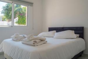a white bed with towels on it with a window at BluWave Luxury Patio Spa Apartment Protaras Riviera in Paralimni