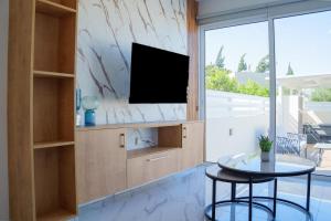 a living room with a tv and a table at BluWave Luxury Patio Spa Apartment Protaras Riviera in Paralimni