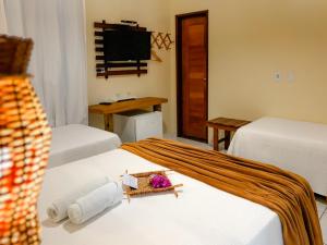 a hotel room with two beds and a tv at Pousada Do Porto in Barreirinhas