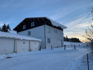 a white building with a black roof in the snow at Chalet Les Jouves in Prémanon