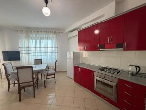 a kitchen with red cabinets and a table with chairs at SunKissed Apartament in Golem