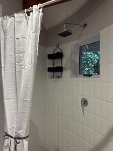 a shower with a white shower curtain in a bathroom at Dune Ridge Cottage in Port Alfred