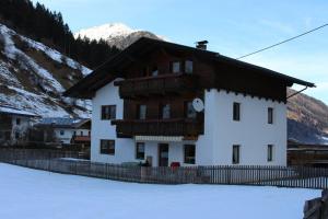 budynek w śniegu z płotem przed nim w obiekcie Haus Gabi w Neustift im Stubaital