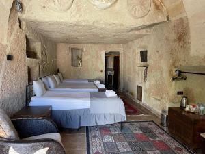 a bedroom with two beds and a couch in a room at Masal Cave Suites - Where Story Begins in Ürgüp