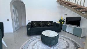 a living room with a black couch and a tv at A-frame-WHITE HOUSE-I in Qusar