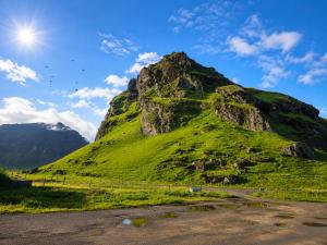 a mountain with green grass on the side of it at Hrutafell Guesthouse in Hvolsvöllur