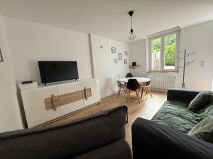 a living room with a couch and a tv and a table at Charmante petite maison - 2 chambres in Homécourt
