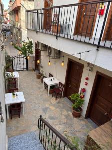an outdoor patio with tables and chairs and a balcony at Lokal Ayvalık Guest House in Ayvalık