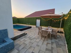 a patio with a table and an umbrella and a pool at A-frame-WHITE HOUSE-I in Qusar