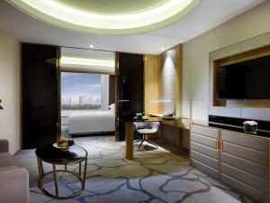 a living room with a bed and a television in a room at Pullman Wenzhou in Wenzhou