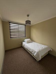 a bedroom with a white bed and a window at Comodo departamento 2 dormitorios con piscina in Quilpué