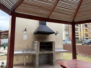 an outdoor kitchen with a stove and a hood at Comodo departamento 2 dormitorios con piscina in Quilpué