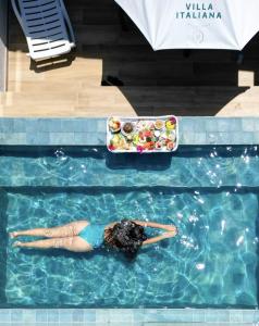 a woman laying in a swimming pool with a plate of food at Pousada de Charme Villa Italiana - Pé na Areia in São Miguel dos Milagres