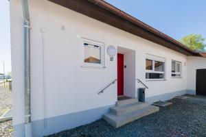 a white house with a red door and stairs at 21 Pure relaxation Apartment in Memmingerberg