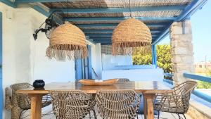 a dining room with a wooden table and rattan chairs at Island Magic - Seaview Villa with Jacuzzi Pool in Ambelas