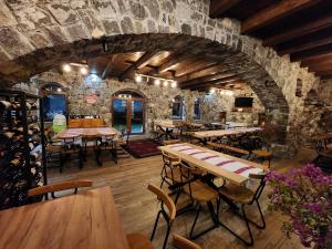 a restaurant with tables and chairs and a stone wall at Bujtina Lepushe Agroturizem in Lëpushë
