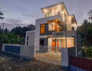 a white house with a fence in front of it at Villa Droom Nest Manado in Manado