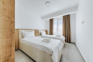 two beds in a hotel room with white sheets at Malik Bay RESIDENTS in Bar