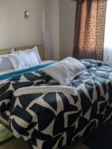 a bed with a black and white comforter and a window at Maneya Apartments in Kabwe