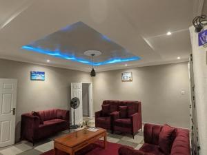 a living room with red chairs and a blue ceiling at Maneya Apartments in Kabwe