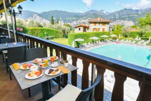a table with food on a balcony with a pool at Park Hotel Val Di Monte ***S in Malcesine