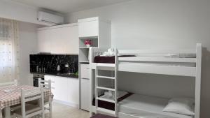 a kitchen with white cabinets and a bunk bed at Amel's Apartments Comfortable Family Stay Near Orikum Beach in Orikum