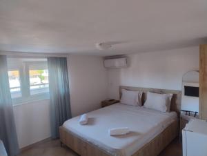 a bedroom with a bed with white sheets and a window at Vila Bolonja in Struga