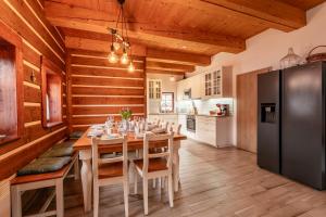 a dining room with a table and a black refrigerator at Chalupy Bret v Krkonoších- prostorná chalupa se 3 apartmány, se saunou nebo vířivkou in Žacléř
