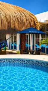 a swimming pool in front of a resort with a straw umbrella at CASTLE WHITE by MONARCA in Ríohacha
