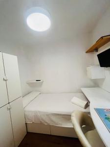 a small white room with a bed and a desk at Casa Leo in Almería