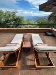 two benches on a balcony with a view of the mountains at Glamping en Casa Viento in Tepoztlán