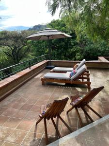 a patio with two chairs and an umbrella at Glamping en Casa Viento in Tepoztlán