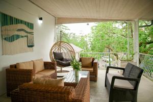 a screened in porch with wicker chairs and a table at Qiwi House in Ureki