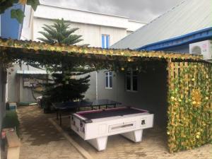 a ping pong table in a backyard with a hedge at Meg Apartment in Asipa