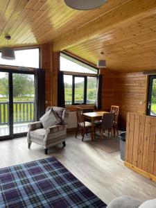 a living room with a table and chairs and windows at Shepherds Lodge in Shiel Bridge