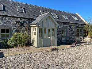 a building with a dog sitting in front of it at Semeil Farm Holiday Lets in Strathdon