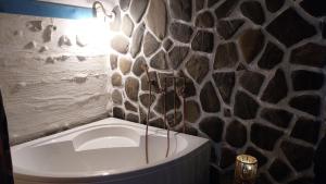 a bath tub in a bathroom with a stone wall at Nook Hill in Comarnic