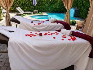 two beds with red rose petals on them next to a pool at Comfort e Casa Lodge Near OR Tambo Airport in Kempton Park