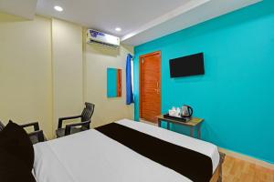 a bedroom with a bed and a blue wall at HOTEL O MYRAA INN in Surūrnagar