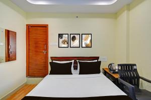 a bedroom with a bed and a desk with two chairs at HOTEL O MYRAA INN in Surūrnagar