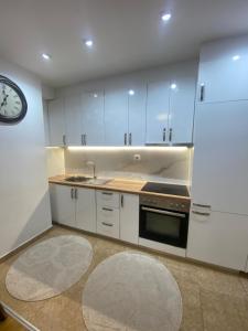 a kitchen with white cabinets and a clock on the wall at AJ Apartments in Kosovo Polje