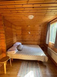 a bedroom with a bed in a log cabin at Kangasjoki Riverside Camp in Suomussalmi